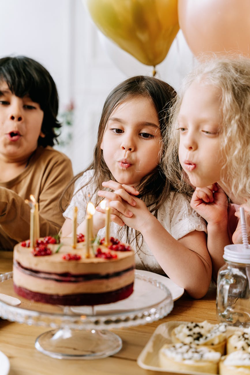 children blowing lighted candles on a cake